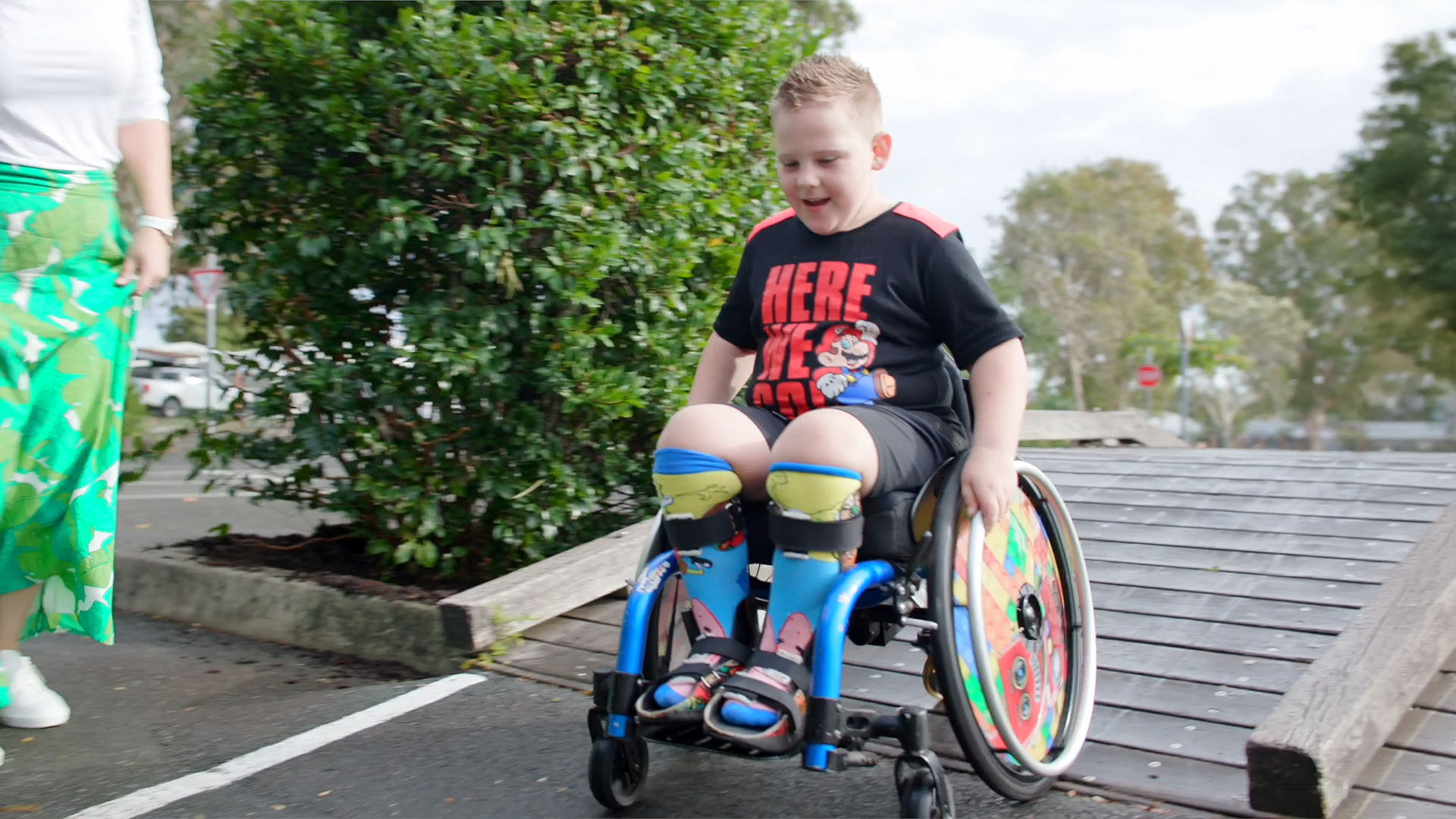 a boy in a wheelchair rolls down a ramp. He is wearing AFOs